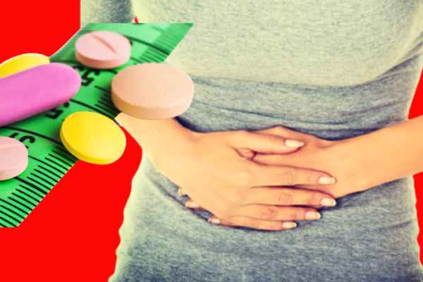 Woman in pain holding stomach next to weight loss drugs.