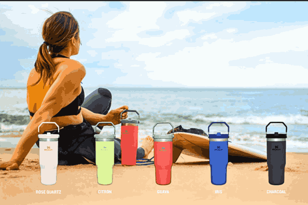 A model on the beach showcasing various Stanley Cups in different colors and sizes, representing the drinkware's diversity and appeal.