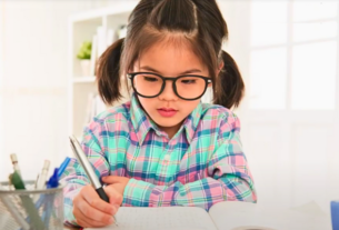A child wearing glasses while studying, illustrating the need for myopia management strategies.