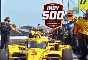 Race cars lined up on the starting grid at the Indy 500, ready to speed off.