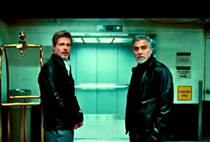 Brad Pitt and George Clooney smiling and standing together on the set of Wolfs.