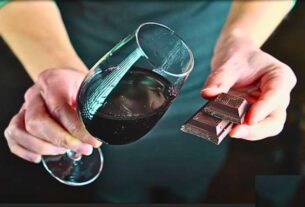 A glass of red wine next to a piece of dark chocolate, highlighting the health benefits of red wine.