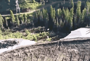A large section of Teton Pass collapsed due to a landslide, showing a gaping chasm in the road with a guardrail hanging over the edge.