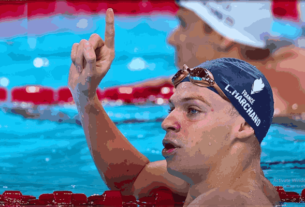 Leon Marchand celebrates winning double gold at the 2024 Paris Olympics, showcasing his medals for the 200m butterfly and 200m breaststroke.