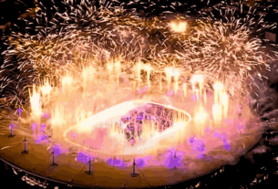 A vibrant scene from the Olympics Closing Ceremony in Paris, featuring a star-studded performance with dazzling lights and cultural displays, symbolizing the transition to Los Angeles as the next host city.